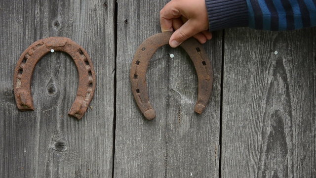 hand hanging wall three iron horseshoes on hammered nail