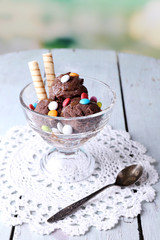 Chocolate ice cream with multicolor candies and wafer rolls in