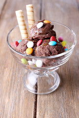 Chocolate ice cream with multicolor candies and wafer rolls in