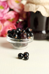 Ripe blackcurrants in bowl and glass jar with tasty jam