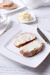 Fresh bread and homemade butter on plate on wooden background