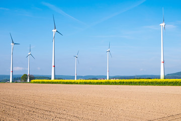 Many windwheels standing behind a barren field