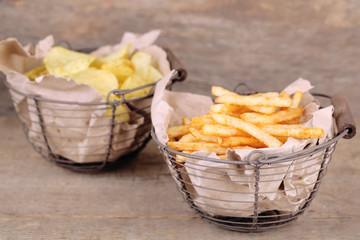 Tasty french fries in metal basket and potato chips