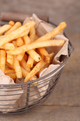 Fototapeta na wymiar Tasty french fries in metal basket on wooden table