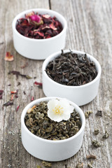 Assorted dry herbal teas in white bowls, vertical