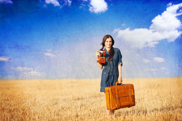 Brunette girl with suitcase on countryside.