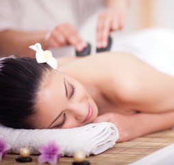 Beautiful woman having a wellness back massage with hot stones