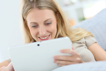 Blond woman at home using digital tablet