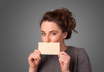 Cute girl holding white card at front of her lips with copy spac