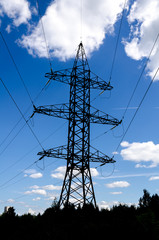 High-voltage power tower over blue sky.