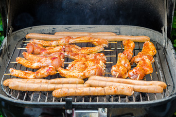 Sausages and chicken wings on smoking grill barbeque