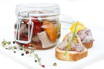 pickled herring in a glass jar with potato canapes
