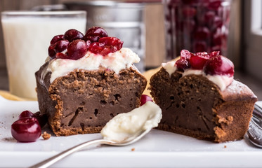 chocolate cake with cream cheese, raw cherry on white plate