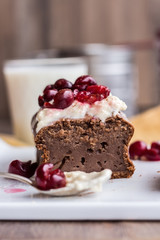 section chocolate cake with cream cheese, raw cherry on white pl