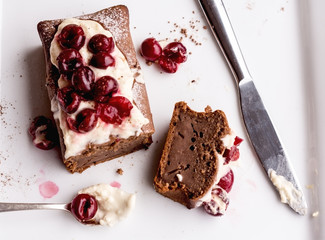 chocolate cake with cream cheese, raw cherry on white plate