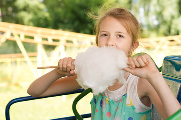 Cute young girl tucking into a ball of candy floss