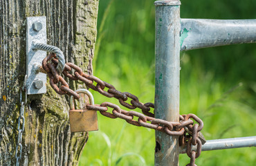 Rusty chain and a closed hardened padlock from close