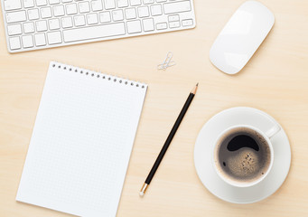Office table with notepad, computer and coffee cup