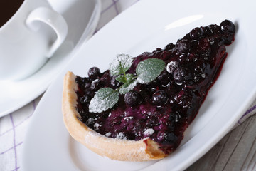 a piece of blueberry pie with mint on a plate and coffee