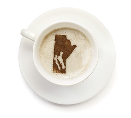 Cup of coffee with foam and powder in the shape of Manitoba.(ser