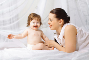 Mom and baby in love, smiling, playing in bed
