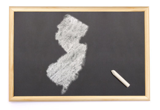 Blackboard with a chalk and the shape of New Jersey drawn onto.