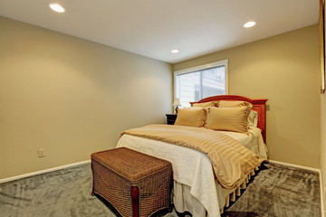 Small bedroom interior with bed and wicker ottoman