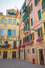 Fototapeta na wymiar Narrow canal among old colorful brick houses in Venice