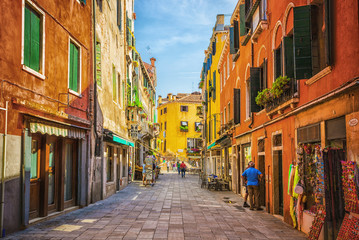 Fototapeta na wymiar Narrow canal among old colorful brick houses in Venice