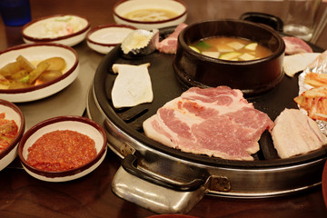 Cooking pork barbecue at the table in Korean restaurant