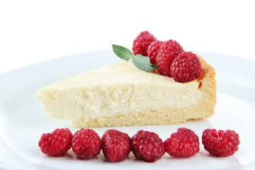 Slice of cheesecake with raspberry on plate, isolated on white