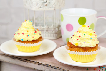Tasty cup cakes with cream on wooden table