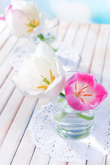 Fototapeta na wymiar Beautiful tulips in bucket in vase on table on light background