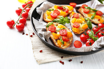 Tasty bruschetta with tomatoes in pan, on table