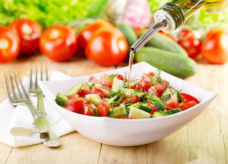 oil pouring  into bowl of vegetable salad
