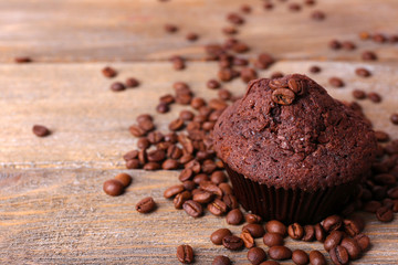 Chocolate muffin and coffee grains on wooden background