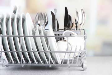 Clean dishes drying on metal dish rack on light background - obrazy, fototapety, plakaty