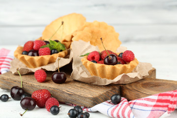 Tasty tartlets with berries on wooden table