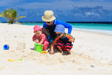 Fototapeta na wymiar Father and kids making sand castle at tropical beach