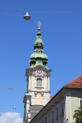 Fototapeta na wymiar Der Kirchturm der Stadtpfarrkirche Graz in der Herrengasse
