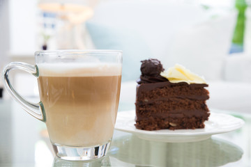 Latte coffee cup and  chocolate cake in background