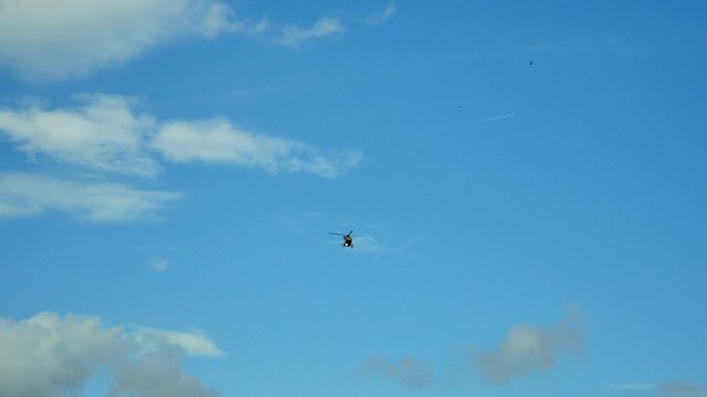 View of a flying helicopter in blue sky clouds