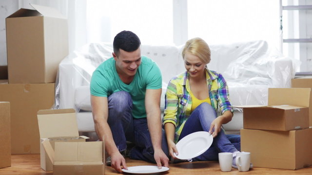 smiling couple unpacking boxes with kitchenware
