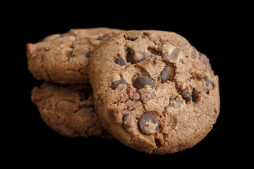 Three chocolate chip cookies isolated on black.