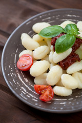 Italian gnocchi with tomato sauce and green basil, vertical shot