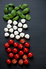 Italian cooking ingredients, black wooden surface, above view