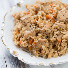 Close-up of pilaf with chicken in a glass plate, studio shot