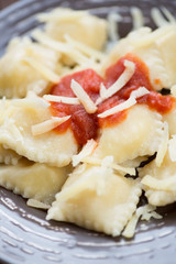 Close-up of ravioli with tomato sauce and parmesan