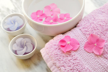 Flowers in a water bowl with a candle and a towel for aromathera