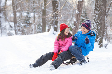 Fototapeta na wymiar boy and girl playing outside on sledges.